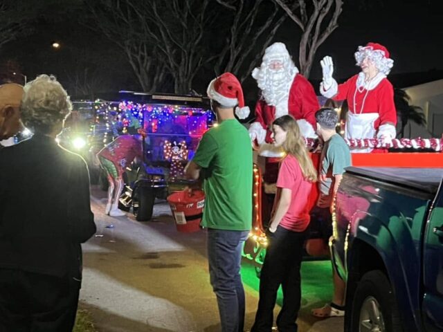 Santa and Mrs. Claus waving from the sleigh to neighbors after dark