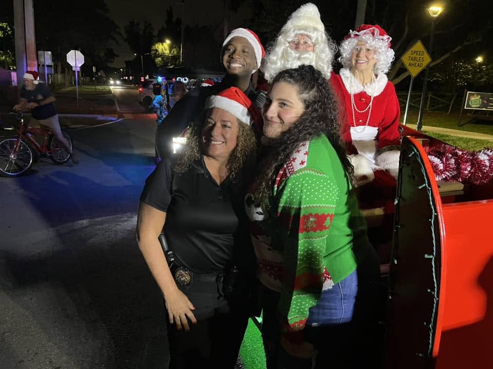 Neighbors in Santa hats posing in front of Santa and Mrs. Claus on the sleigh