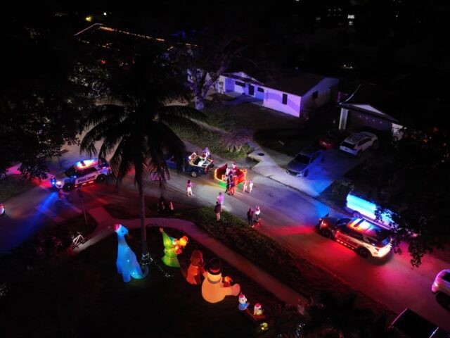 Night view from above of the sleigh’s lights passing decorated homes