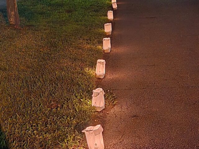 Light Up the Creek: paper bag luminaries glowing along a neighborhood sidewalk