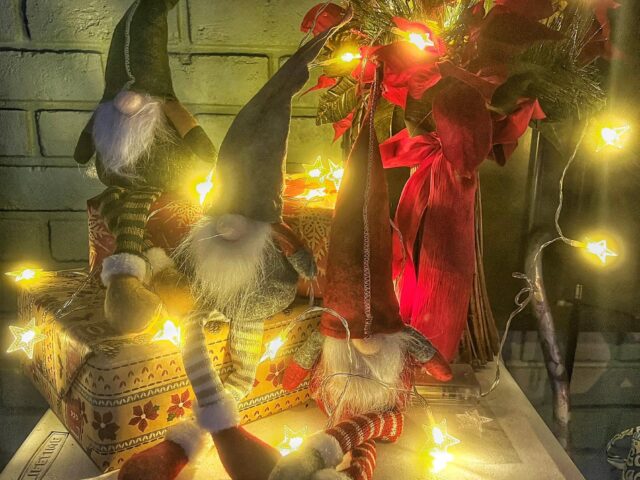 Christmas gnomes and warm string lights decorating a front porch