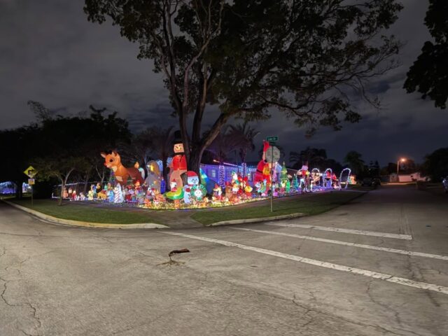 A corner yard lined with glowing inflatable decorations at dusk