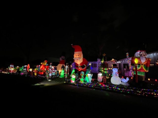 A long row of inflatable Santas and snowmen glowing at night